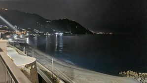 Une vue nocturne de la côte, avec une route, un pont et les lumières d'une ville lointaine.