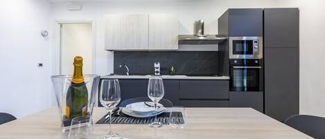 A modern kitchen with a dining table set for two, a microwave, and a built-in oven.