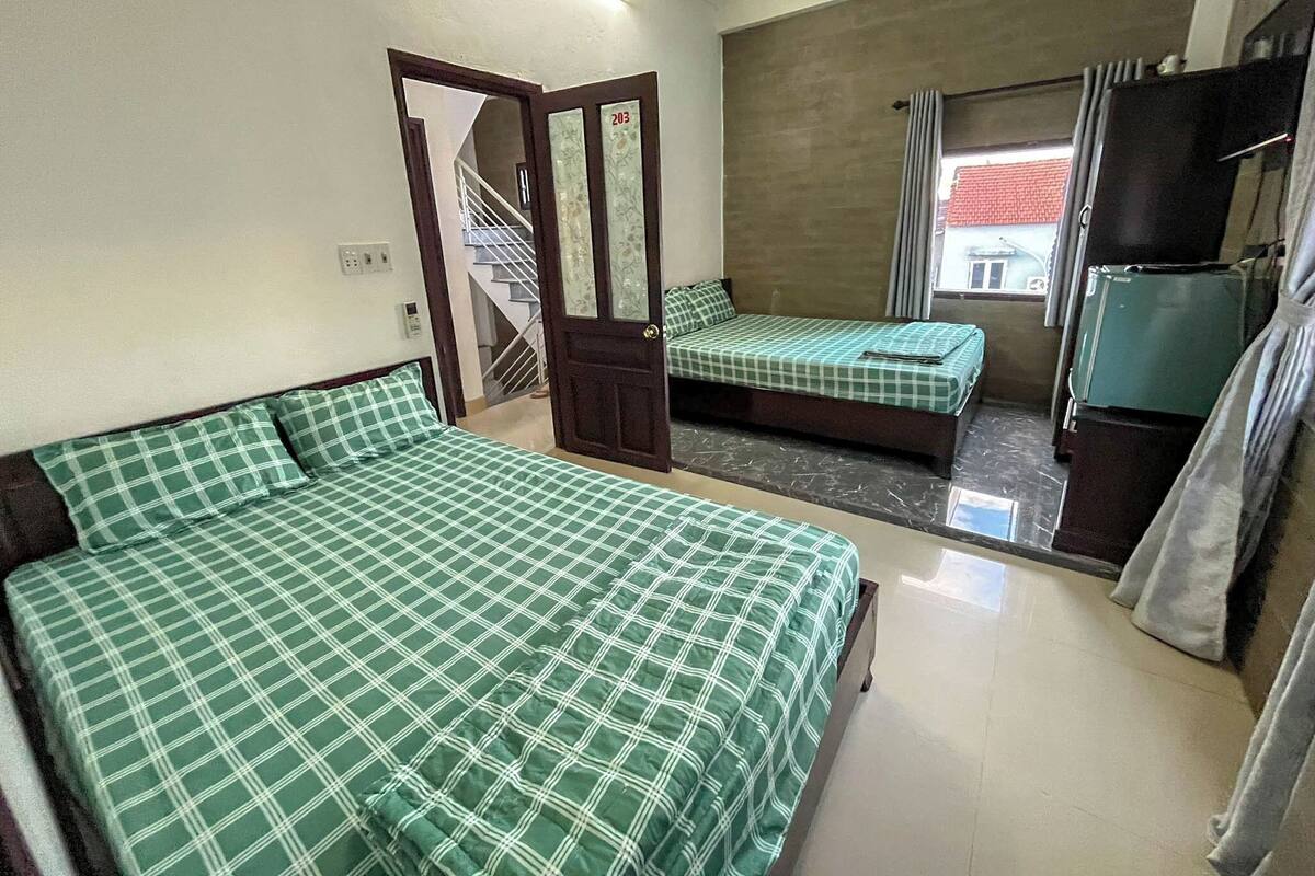 Una habitación con dos camas, una escalera, un televisor y un refrigerador.
