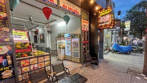 Um restaurante com quadro de cardápio, cadeiras e um refrigerador.