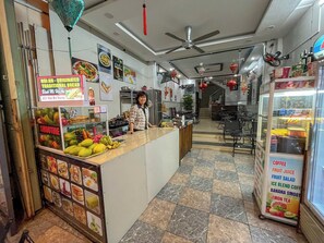 Un café avec un comptoir où sont exposés des fruits et un tableau affichant le menu.