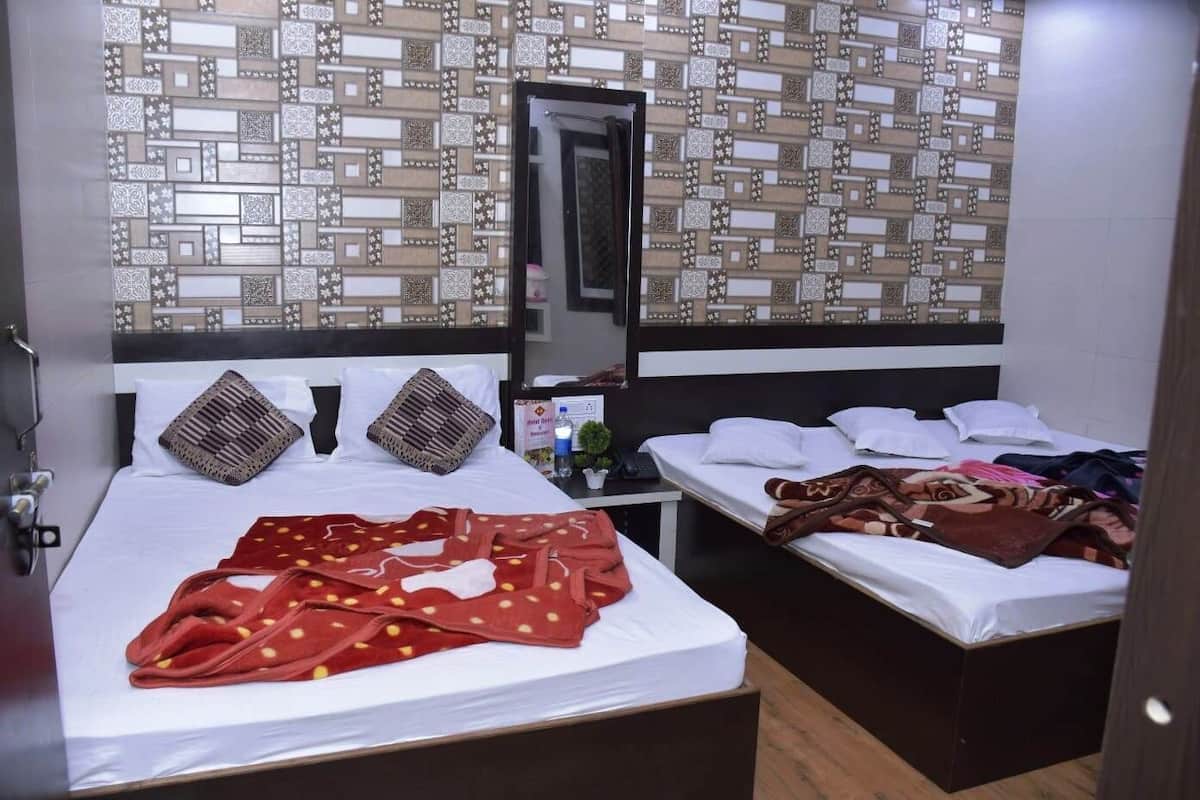 A hotel room with two beds, a large mirror, and a patterned wall.
