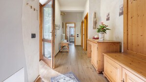 Un pasillo con suelo de madera, un armario de madera y una puerta que da a otra habitación.