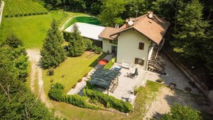 Una casa con jardín, cancha de tenis y piscina.
