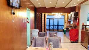 Zona pranzo con soffitto alto, illuminazione a incasso e televisore a parete.