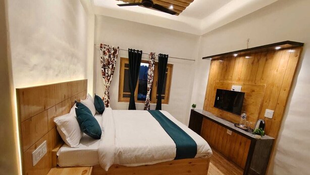 Una camera da letto moderna con un letto in legno, un comodino, una TV integrata e una scrivania in legno.