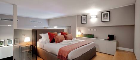 A modern bedroom with a bed, bedside tables, a desk, and a chair.