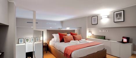 A modern bedroom with a large bed, bedside tables, a wardrobe, and framed pictures on the wall.