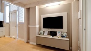 A modern living room with a flat-screen TV mounted on a wall, a built-in entertainment unit below, and a wooden floor. - Milan Style (Milan)