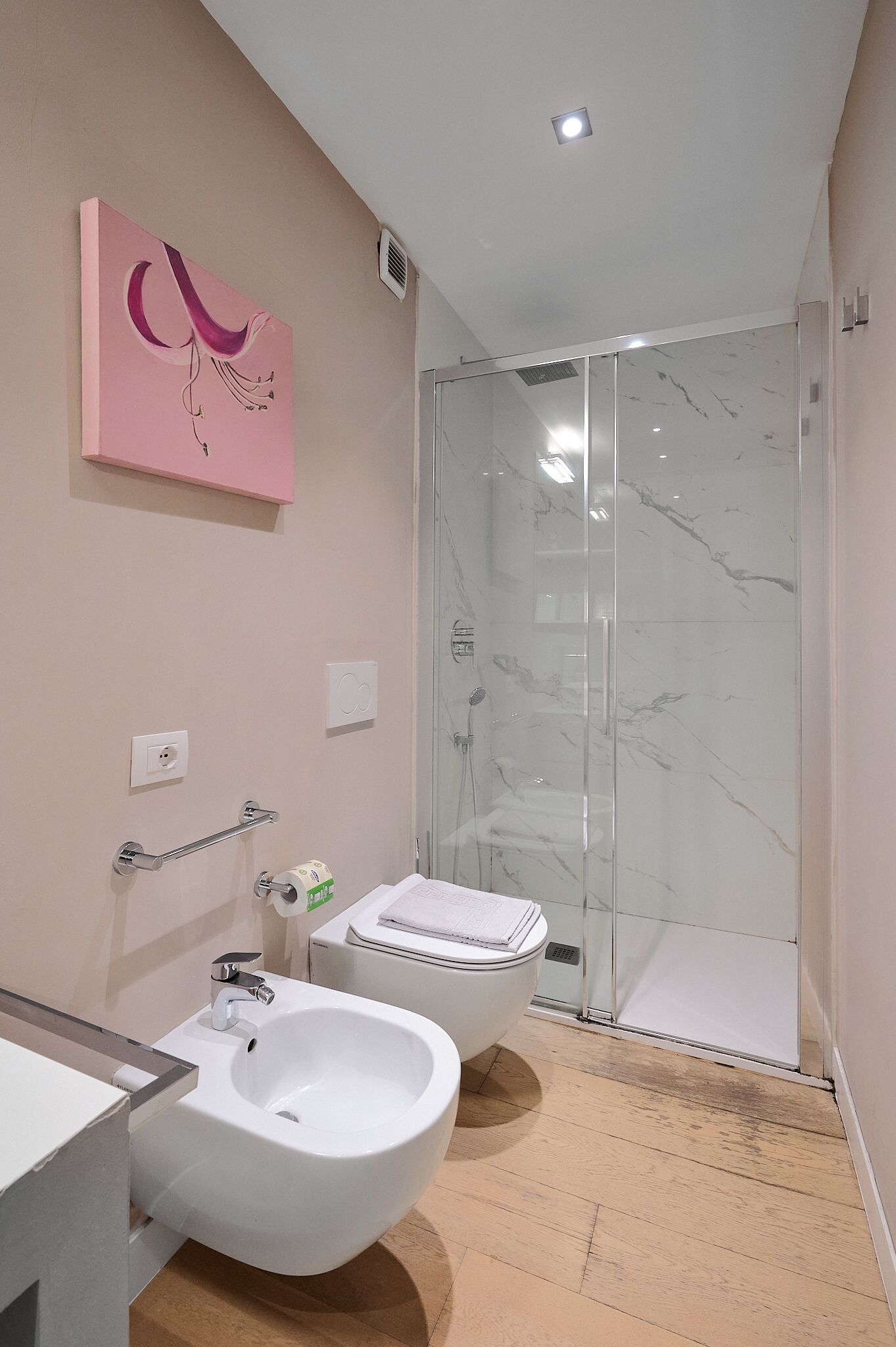 Une salle de bain moderne équipée d’un bidet, de toilettes et d’une douche à parois de verre.
