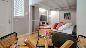 A modern hotel room with a wooden ceiling, a bed with white and red pillows, a TV, and a painting on the wall. - Milan Style (Milan)
