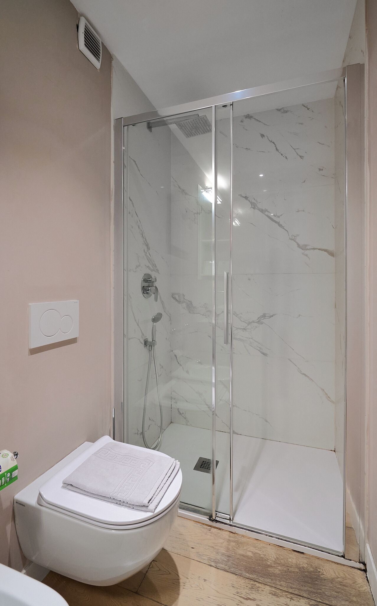 A bathroom with a glass-enclosed shower, a toilet, and a towel rack.