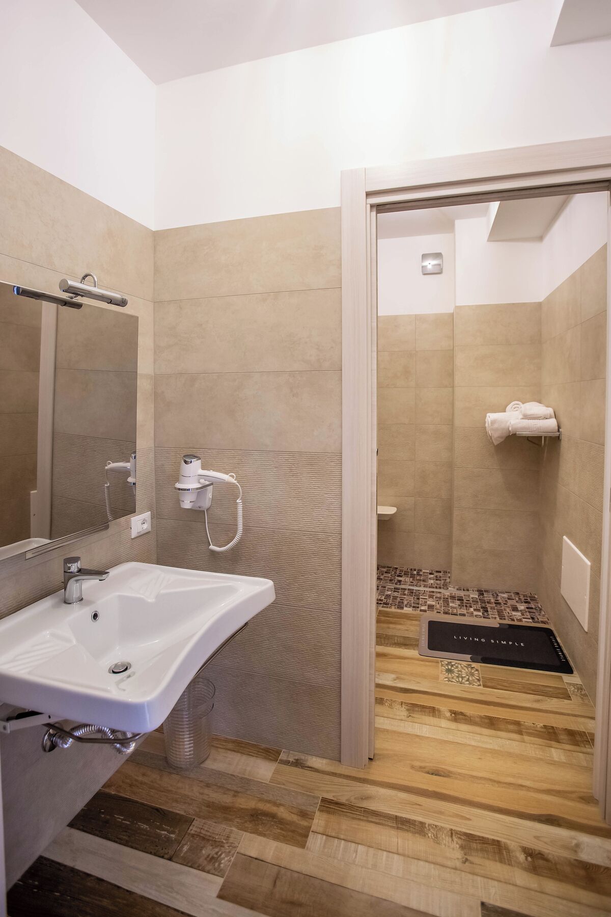 A modern bathroom with a large sink, a hairdryer, and a shower area.