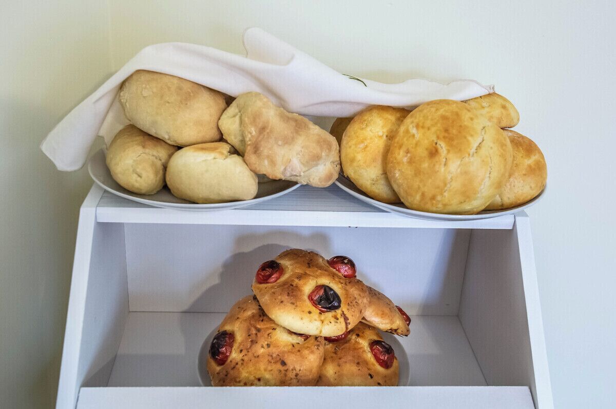 A white box containing various types of bread, including rolls and a bread with raisins.