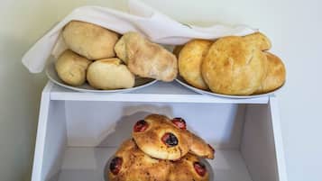 A white box containing various types of bread, including rolls and a bread with raisins.