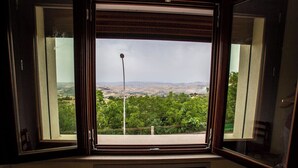 Une pièce dotée d’une grande fenêtre donnant sur un paysage verdoyant et des collines lointaines.