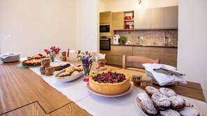 Une table à manger dressée avec divers desserts, et une cuisine en arrière-plan.