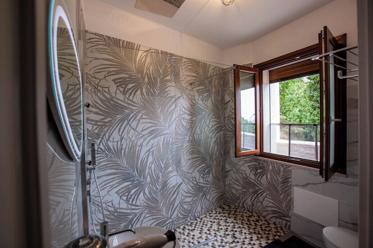 Un baño con ducha, inodoro y ventana.