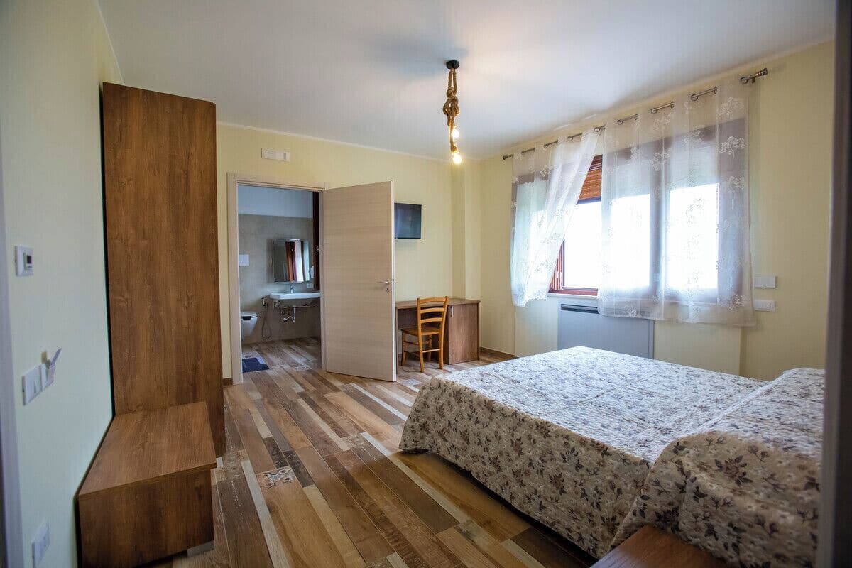 Een slaapkamer met een houten garderobe, een bureau en een bed met bloemenbeddengoed.