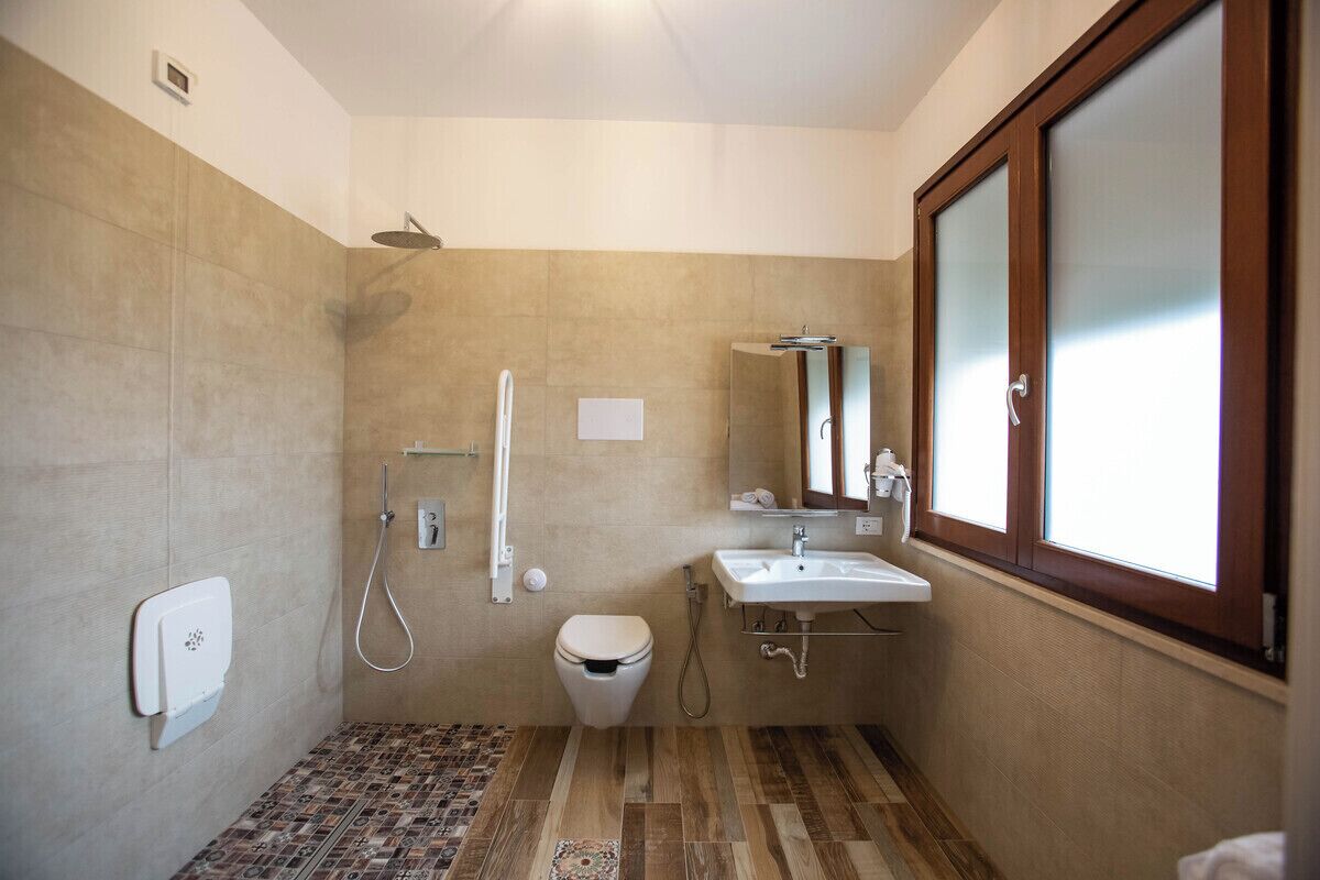 A bathroom with a shower, toilet, sink, and a window.
