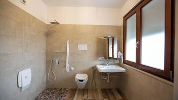 A bathroom with a shower, toilet, sink, and a window.