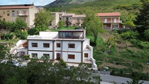 Un immeuble à plusieurs étages doté de balcons, entouré de verdure et de collines.