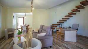 Un salon moderne avec un canapé, des fauteuils, une table à manger et un escalier.