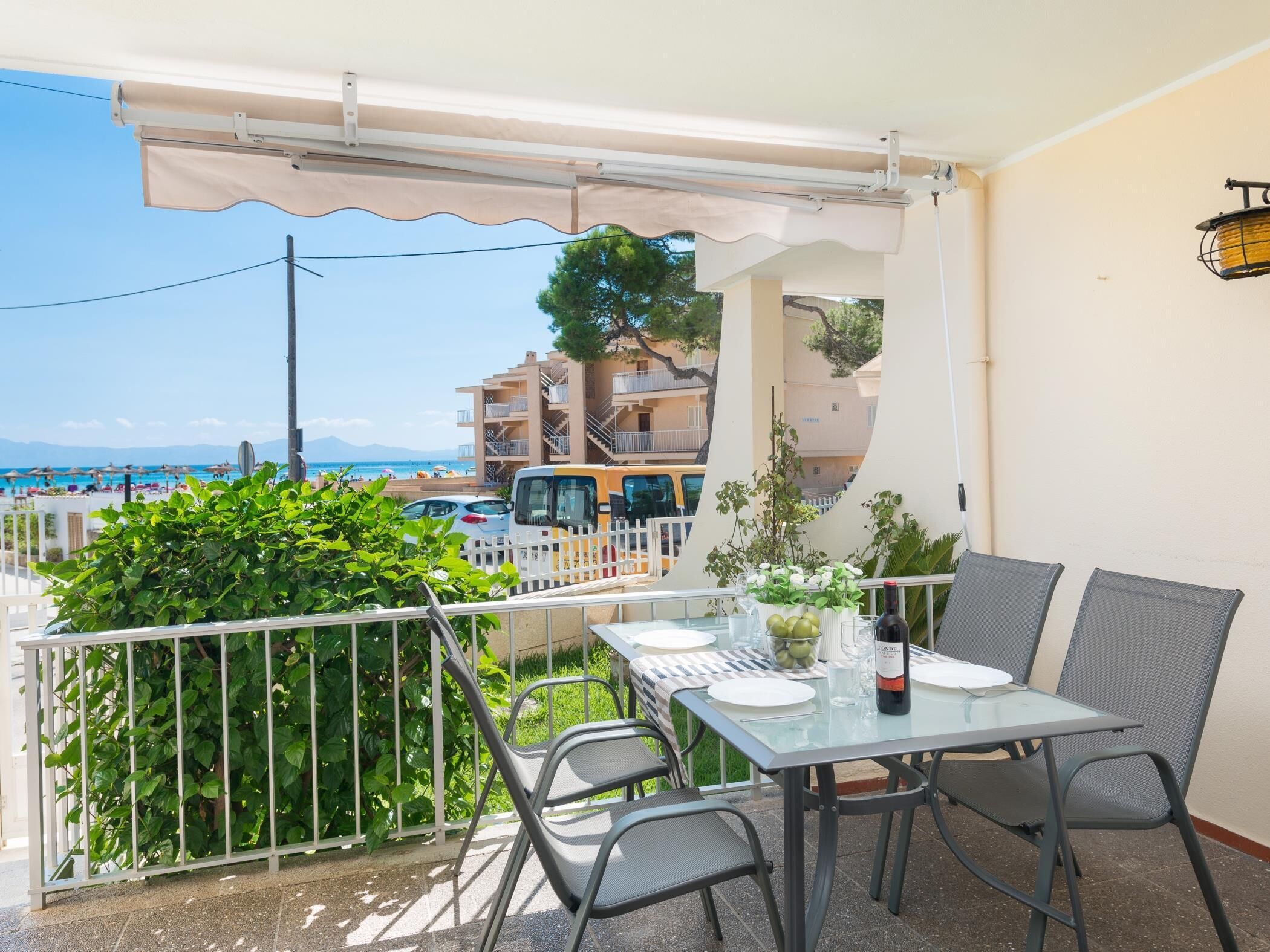 A balcony with a table set for two, overlooking a beach and residential buildings.