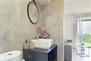 A modern bathroom with a white sink, a round mirror, and a flower vase. - Country House 'Villa Andreas' with Sea View, Private Terrace and Wi-Fi (Athani)