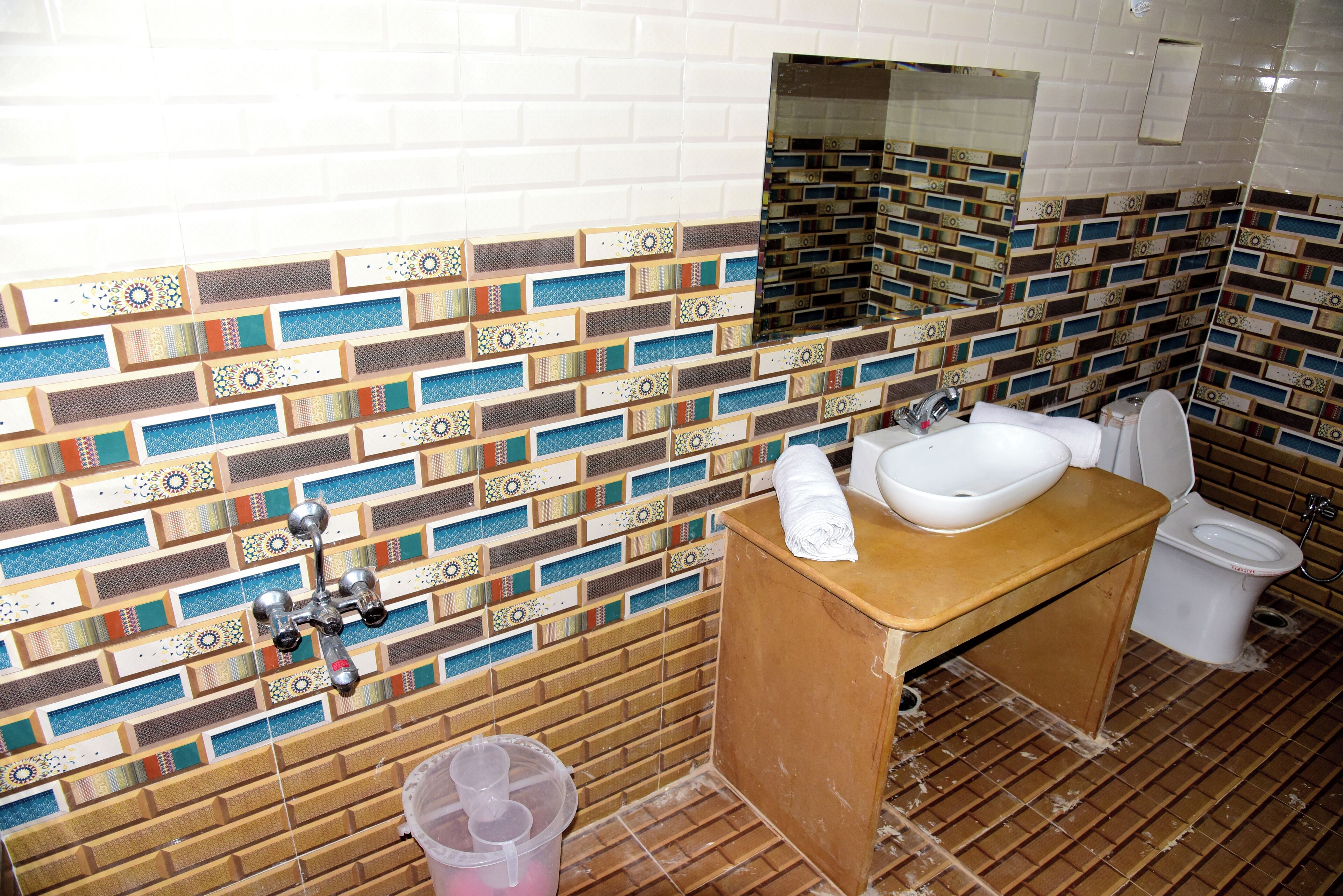 A bathroom with a tiled wall, a sink, a toilet, and a mirror.