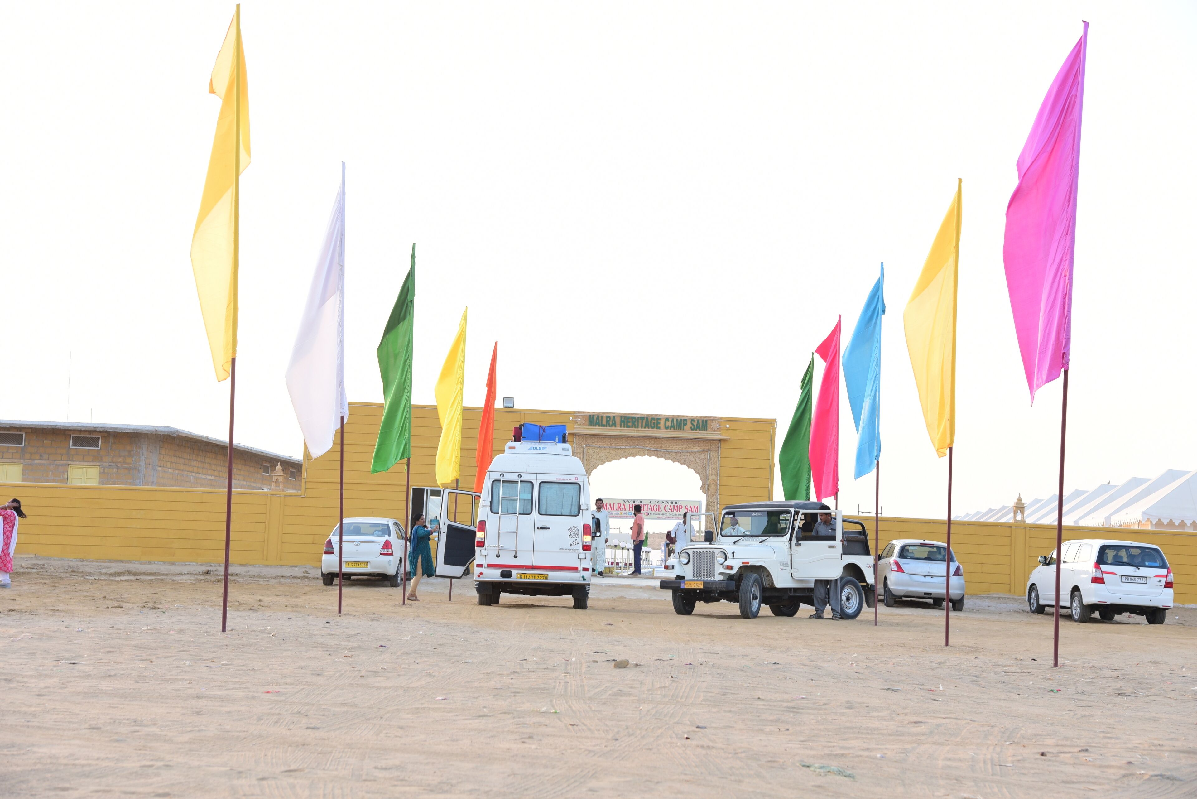A parking area with several vehicles and colorful flags.