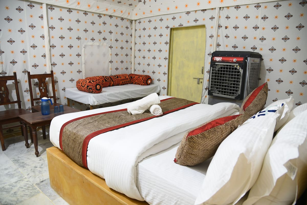 Habitación de hotel con dos camas, una silla de madera, una mesa y un calentador.