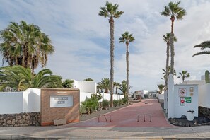 Un sendero que lleva al Parque Shangrila, con palmeras y un muro blanco.