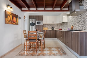 Una cocina con armarios de madera, un refrigerador, un microondas y un salpicadero de azulejos.