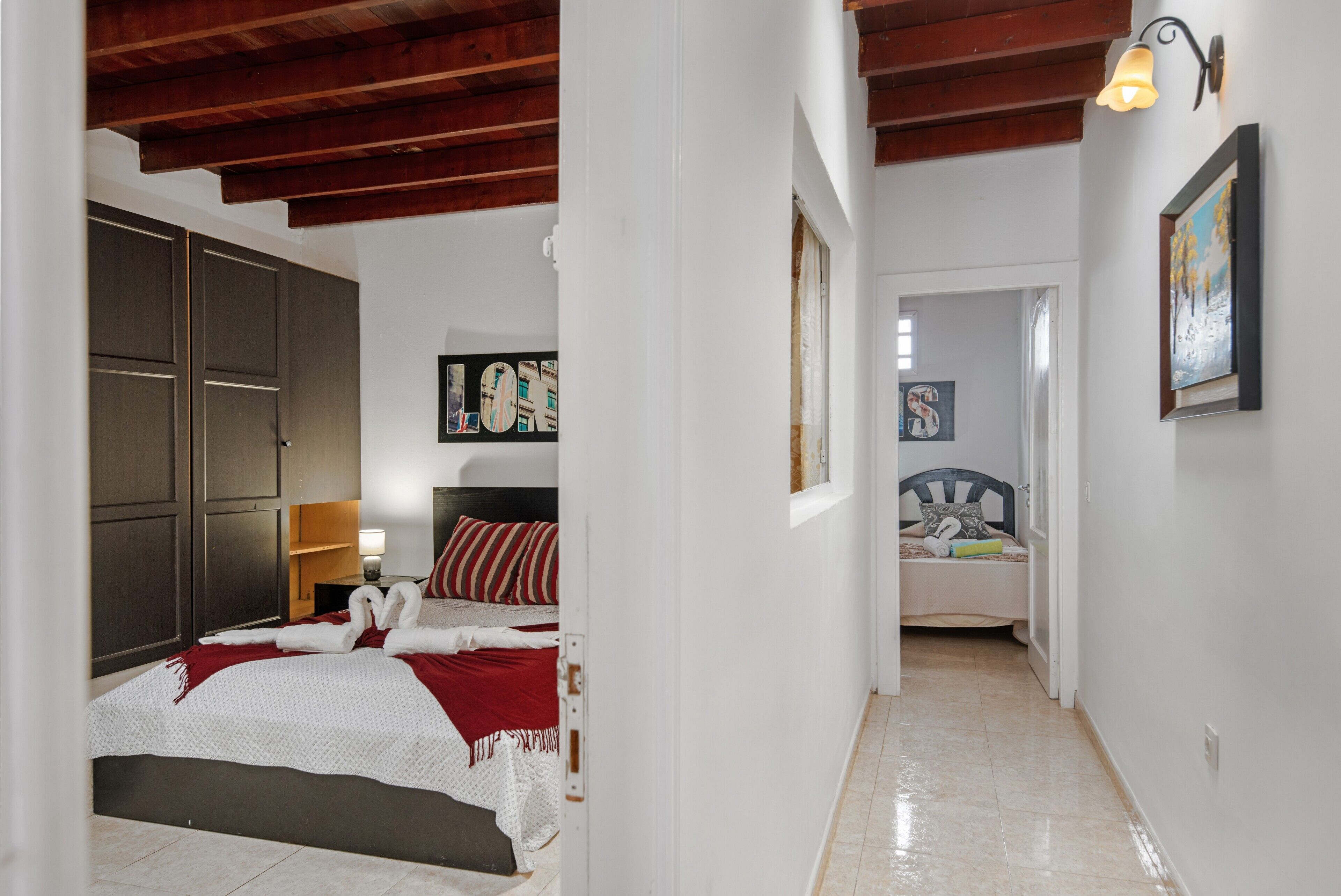 Une chambre à coucher avec un lit, une armoire, une table de chevet et un tableau au mur.