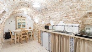 A kitchen with stone walls, a wooden dining table, and a built-in oven. - Holiday Home 'Dimora Marter' with Private Terrace, Wi-Fi and Air Conditioning (Conversano)