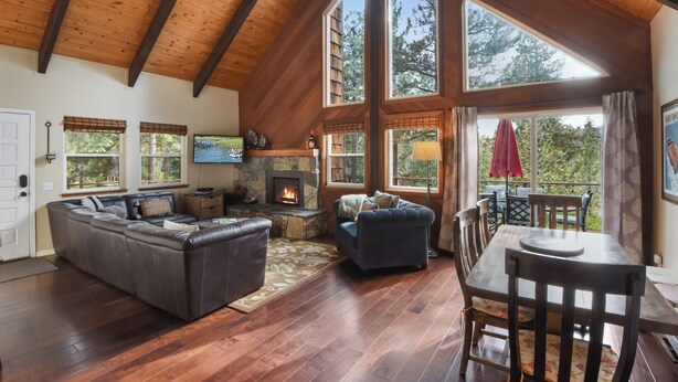 A spacious living room with a fireplace, large windows, and a dining area. - The Sunset Getaway - Hot Tub, Dog Friendly (Carnelian Bay)