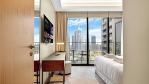 A modern hotel room with a city view, a desk, a bed, and a mounted TV. - WYZ RENT|3 BDs Address Opera-Burj Khalifa (Dubai)