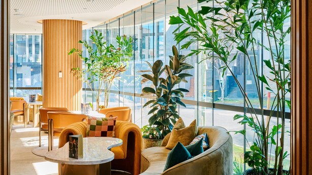 Un vestíbulo moderno con un columnario de madera curvada, asientos cómodos y amplios ventanales con vistas a la ciudad.