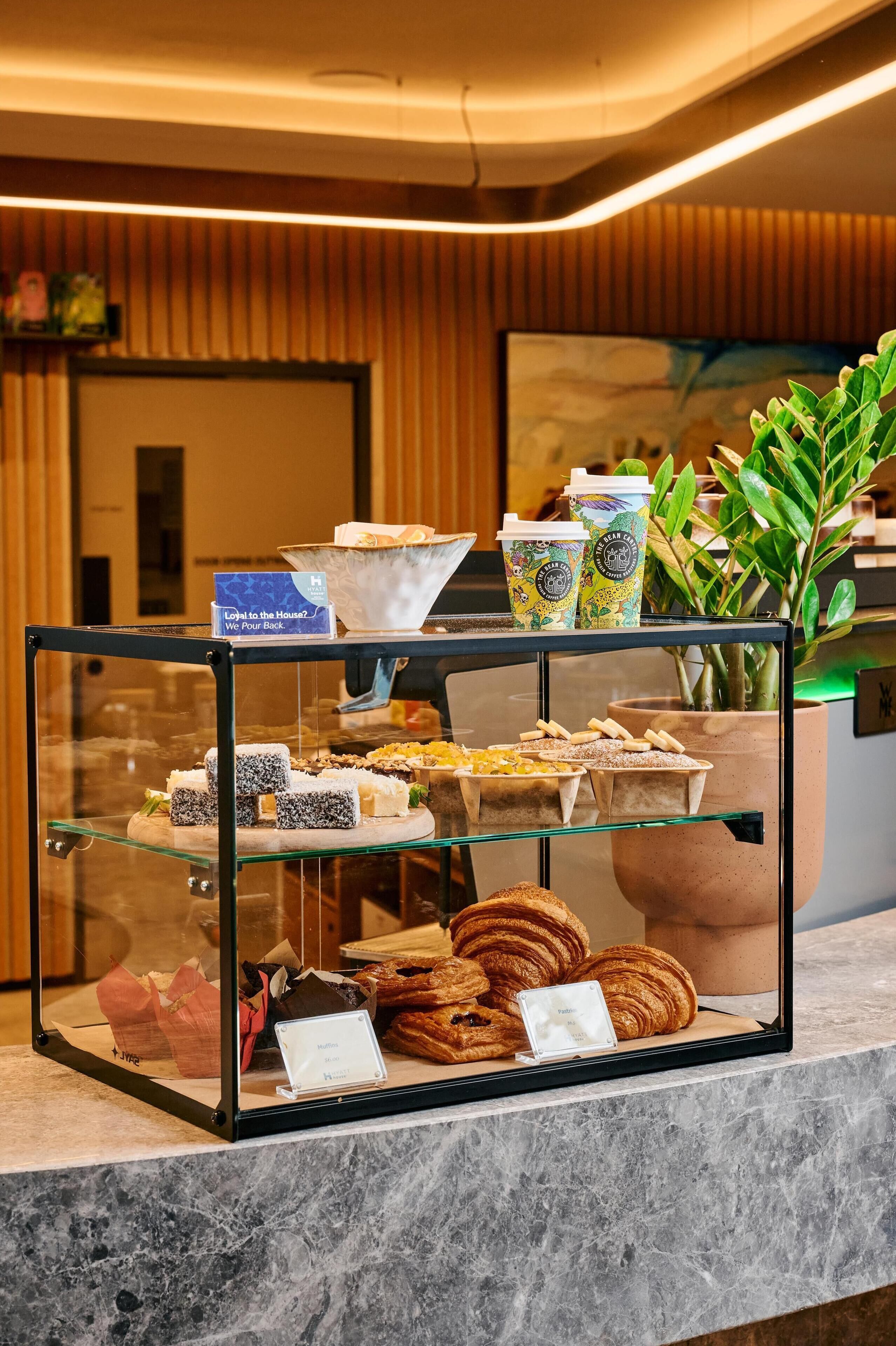 Una vitrina con varios pasteles y una estación de café en el vestíbulo de un hotel.
