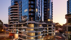 Un edificio de varios pisos con un diseño arquitectónico moderno, que cuenta con balcones y ventanas grandes.