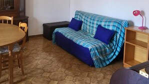 Une pièce comprenant une table à manger, un canapé, un meuble et un tableau accroché au mur.
