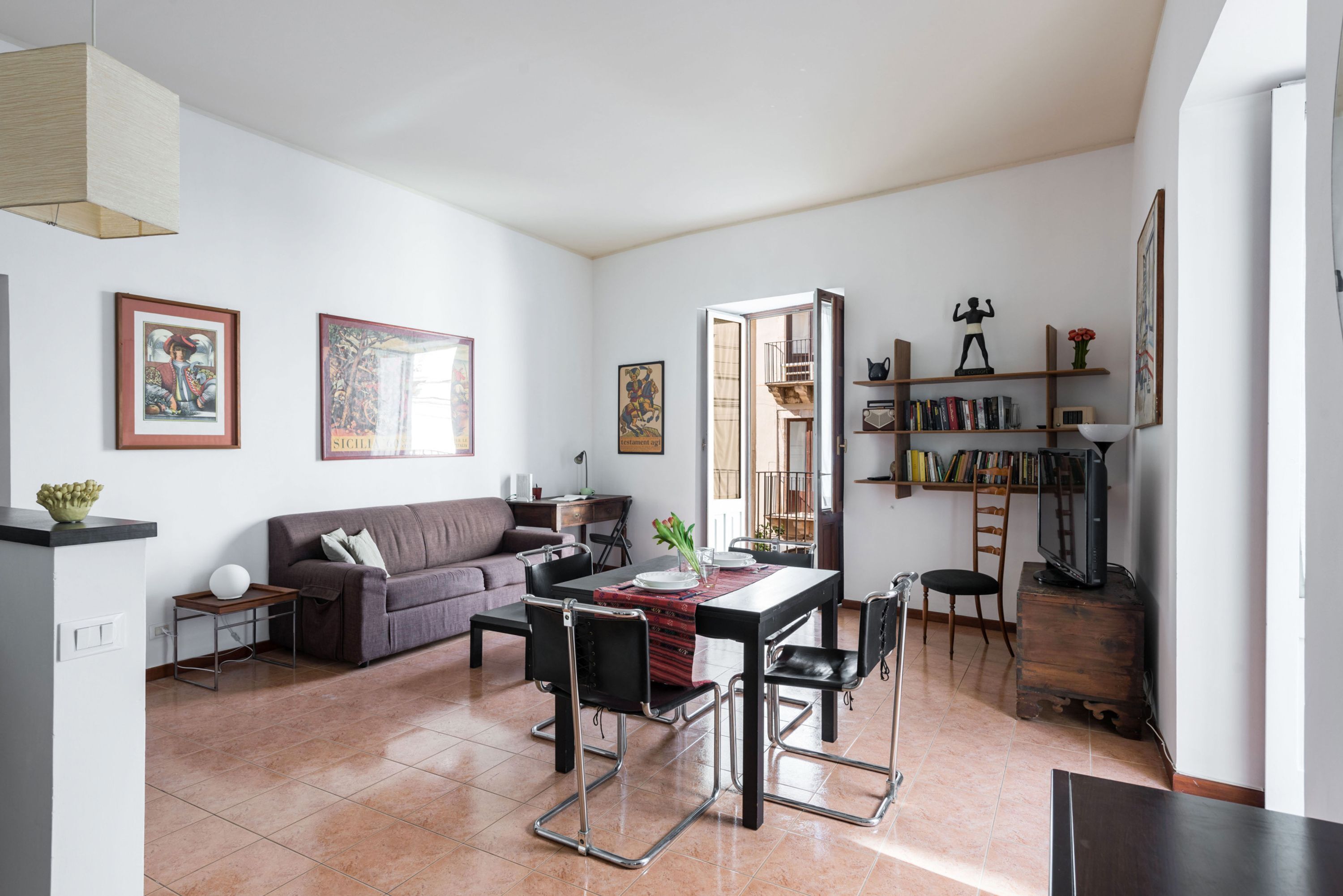 A spacious living area with a dining table, chairs, a sofa, and a bookshelf.