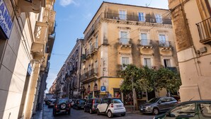 A narrow street lined with multi-story buildings, parked cars, and a visible parking sign. - Casa all Anfiteatro di Catania by Wonderful Italy (Catania)