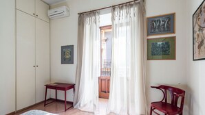 A room with a bed, a desk, a chair, an air conditioning unit, and a view of the outside through a door. - Casa all Anfiteatro di Catania by Wonderful Italy (Catania)