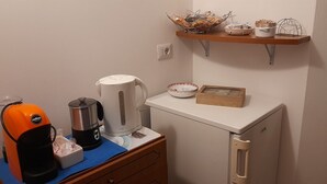 Una kitchenette equipada con cafetera, hervidor y un refrigerador pequeño.