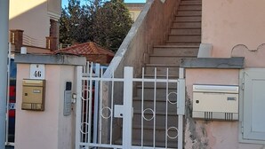 Un edificio residencial con entrada porticada, una escalera y un buzón.