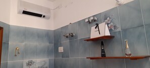A bathroom with blue tiles, a shower, a vanity with a mirror, and a hanging towel rack.
