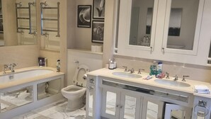 Moderni kylpyhuone, jossa on kaksi erillistä pesuallasta, suuri peili ja wc.