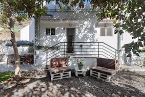 Un bâtiment blanc doté d’un balcon, d’une terrasse et d’un escalier menant à l’entrée.